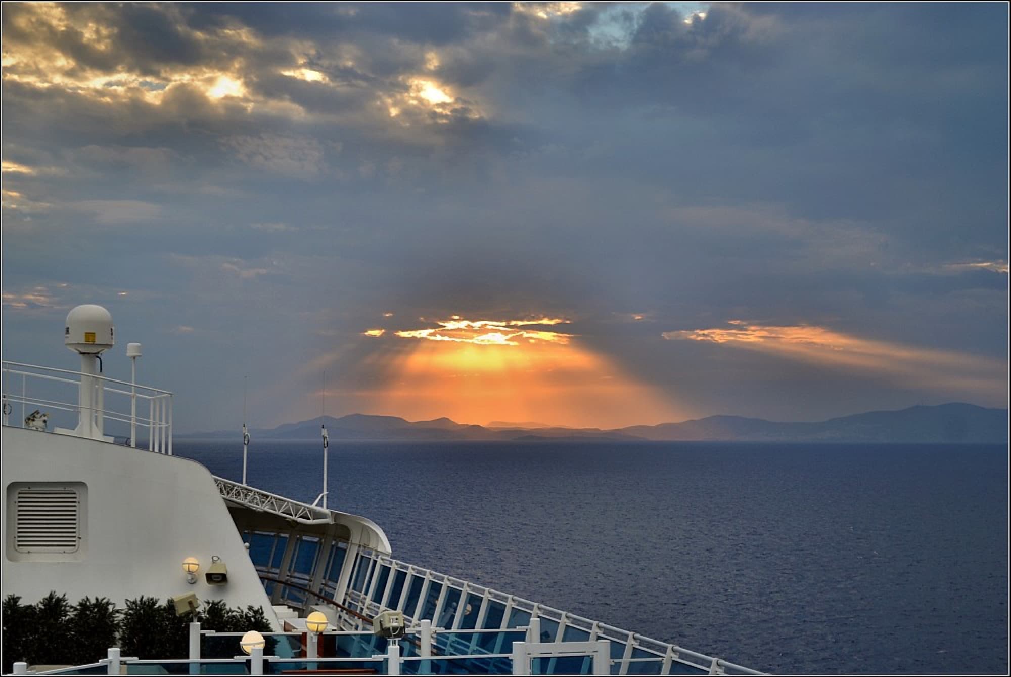 Cruise ship deck at golden hour with passengers at the rail